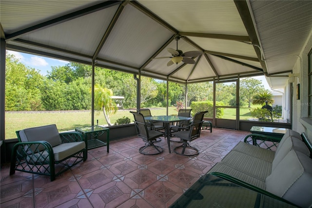 sunroom with lofted ceiling with beams, ceiling fan, and plenty of natural light