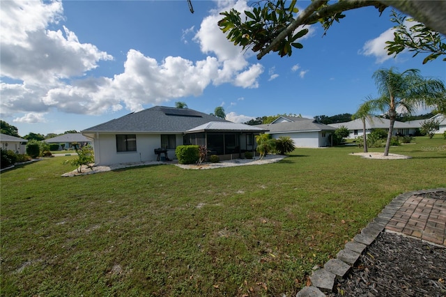 rear view of property featuring a yard and a sunroom