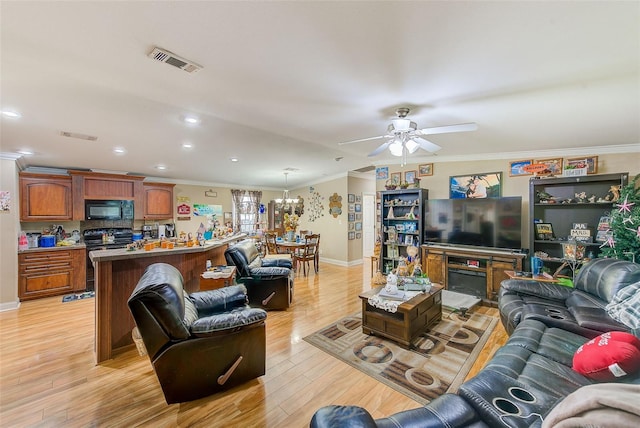 living room featuring ceiling fan with notable chandelier, light wood-type flooring, a fireplace, and crown molding