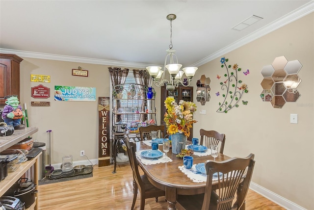 dining space featuring crown molding, light hardwood / wood-style floors, and an inviting chandelier