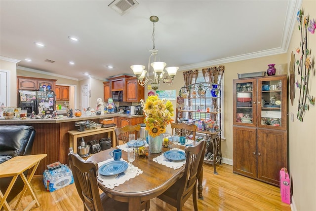 dining room featuring an inviting chandelier, light wood-type flooring, and crown molding