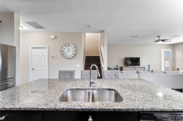kitchen featuring dishwashing machine, an island with sink, a sink, freestanding refrigerator, and open floor plan