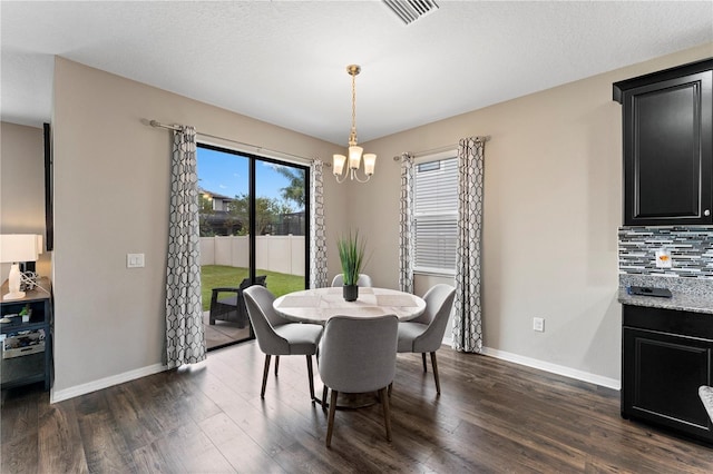 dining space featuring baseboards, dark wood finished floors, an inviting chandelier, and visible vents