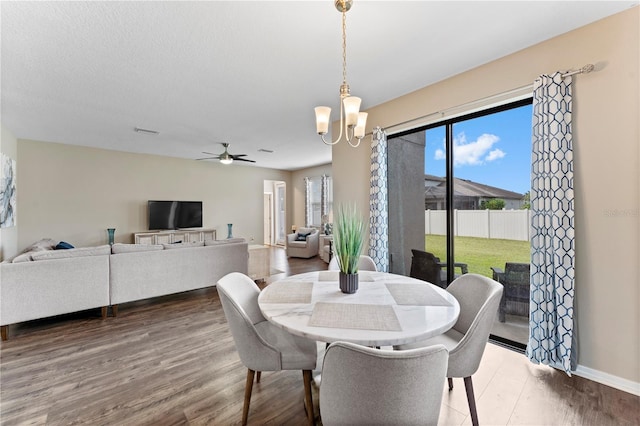 dining area with a textured ceiling, wood-type flooring, and ceiling fan with notable chandelier