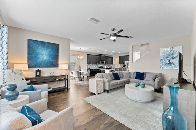 living room featuring a textured ceiling, ceiling fan with notable chandelier, and dark hardwood / wood-style floors