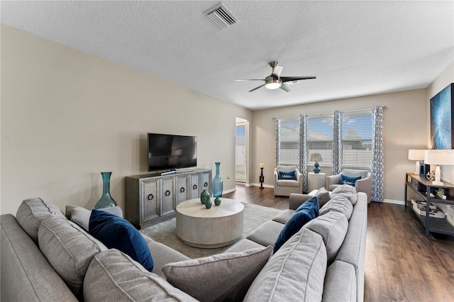 living room featuring a textured ceiling, visible vents, dark wood finished floors, a ceiling fan, and baseboards