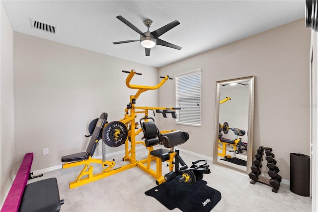 workout room with a textured ceiling, light colored carpet, and ceiling fan