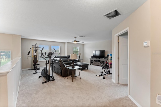 workout room featuring baseboards, ceiling fan, visible vents, and light colored carpet