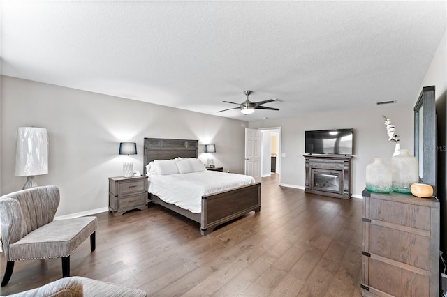 bedroom featuring ceiling fan, hardwood / wood-style flooring, and a textured ceiling