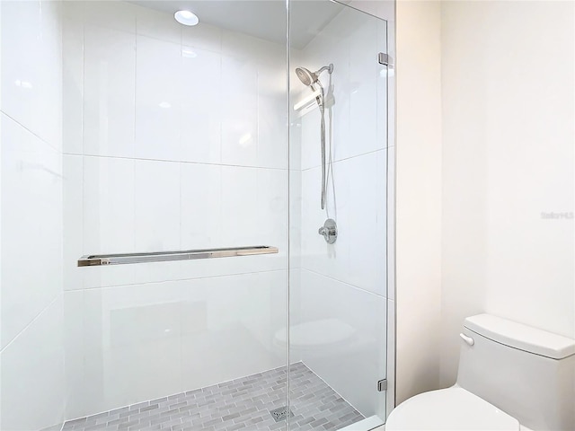 bathroom featuring a shower with shower door and toilet