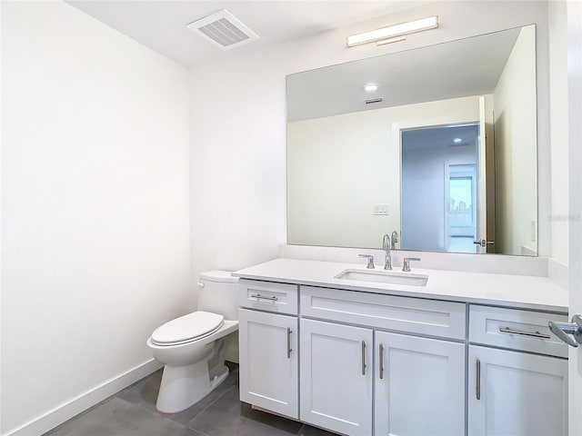 bathroom with toilet, vanity, and tile patterned floors