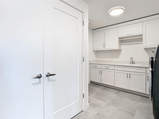 kitchen featuring light tile patterned flooring, white cabinets, and sink