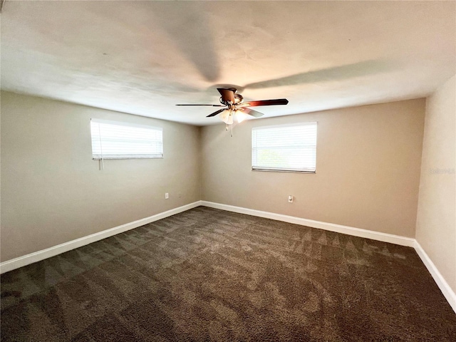 spare room featuring dark carpet and ceiling fan