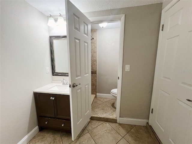 bathroom with vanity, a textured ceiling, a tile shower, tile patterned flooring, and toilet