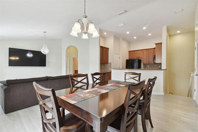 dining space featuring light hardwood / wood-style flooring, vaulted ceiling, and an inviting chandelier