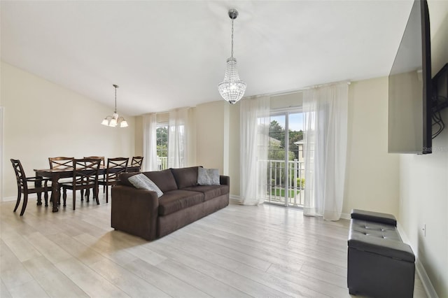 living room featuring a chandelier, light wood-type flooring, and a healthy amount of sunlight