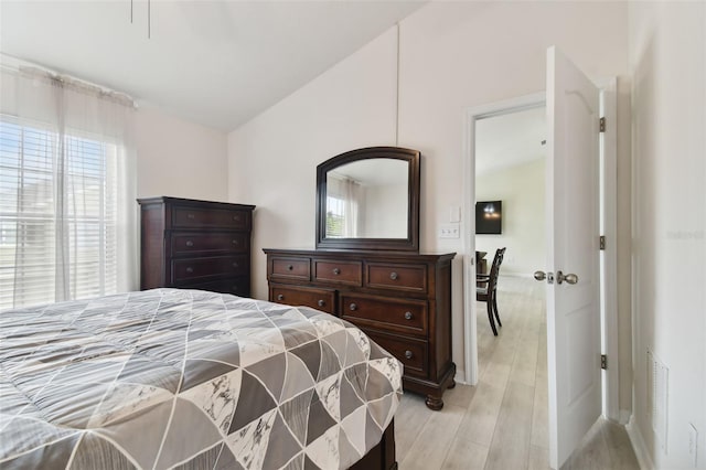 bedroom with light hardwood / wood-style floors, multiple windows, and lofted ceiling