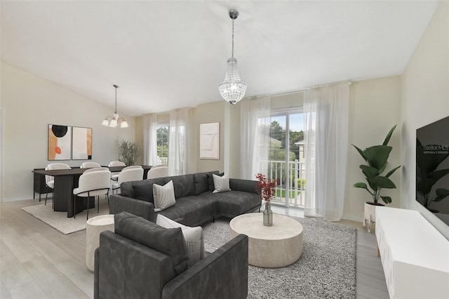 living room with a chandelier, vaulted ceiling, light hardwood / wood-style floors, and plenty of natural light