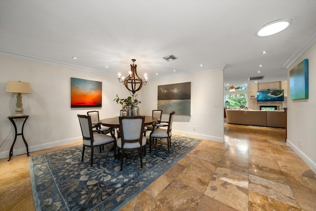 dining room featuring a fireplace, crown molding, and an inviting chandelier