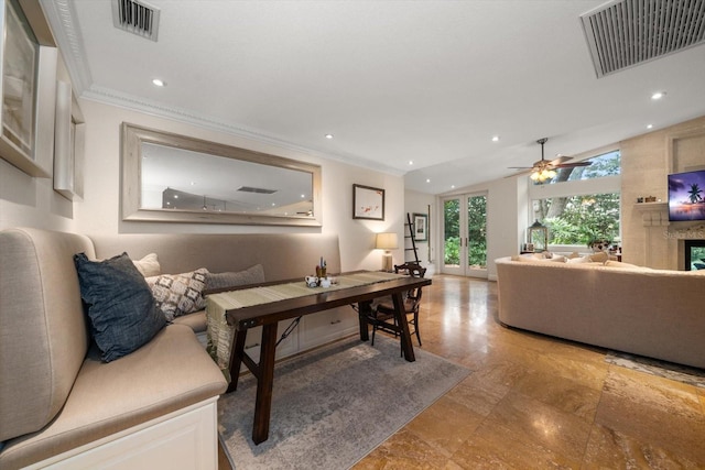 living room with ceiling fan, ornamental molding, a high end fireplace, and vaulted ceiling