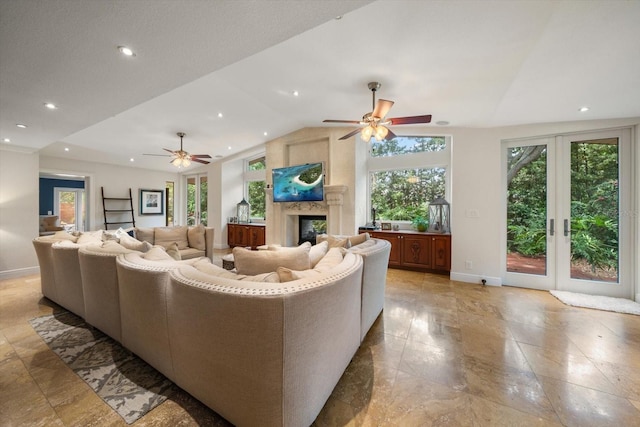 living room with ceiling fan, vaulted ceiling, a high end fireplace, and french doors