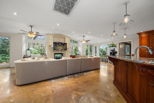 living room featuring a high end fireplace, plenty of natural light, and ceiling fan