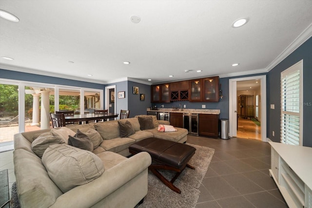 living room featuring wine cooler, wet bar, dark tile patterned floors, and ornamental molding