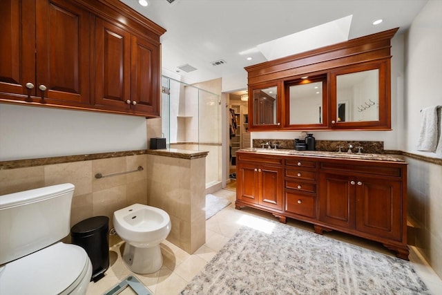 bathroom with tile patterned floors, a bidet, toilet, a shower with shower door, and tile walls