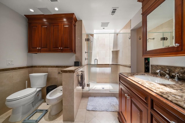 bathroom featuring vanity, a shower with door, a bidet, tile patterned floors, and tile walls