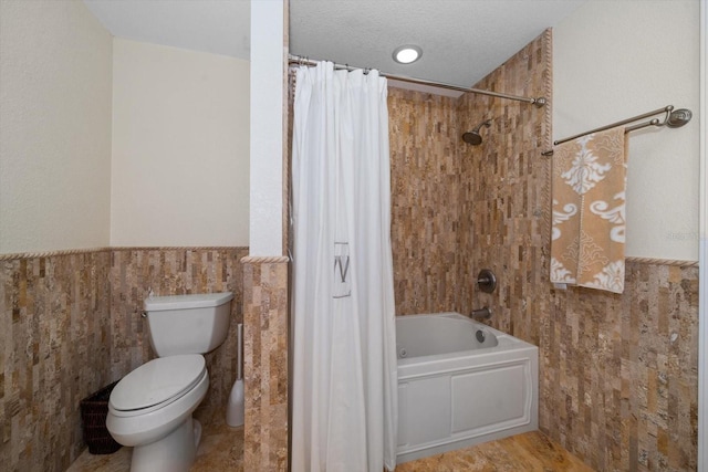 bathroom featuring tile walls, shower / tub combo with curtain, a textured ceiling, and toilet