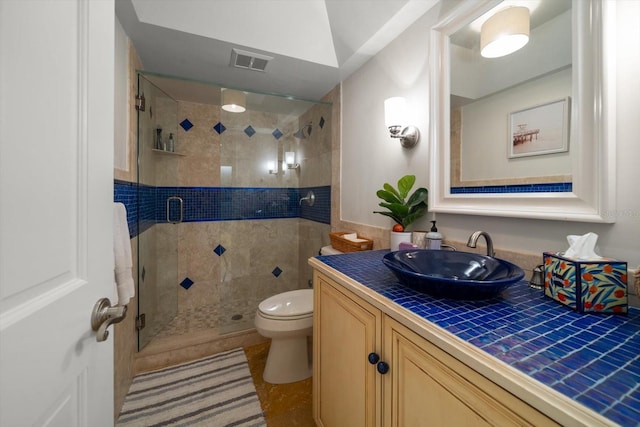 bathroom featuring tile patterned flooring, vanity, toilet, and walk in shower