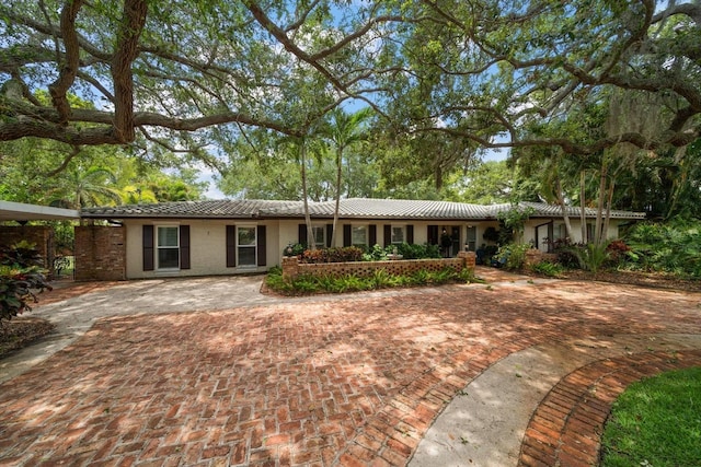 view of front facade featuring a tile roof, driveway, and stucco siding