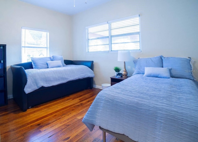 bedroom featuring multiple windows and dark hardwood / wood-style flooring