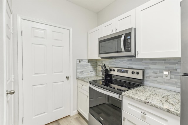 kitchen featuring white cabinetry, light stone countertops, light hardwood / wood-style flooring, and stainless steel appliances