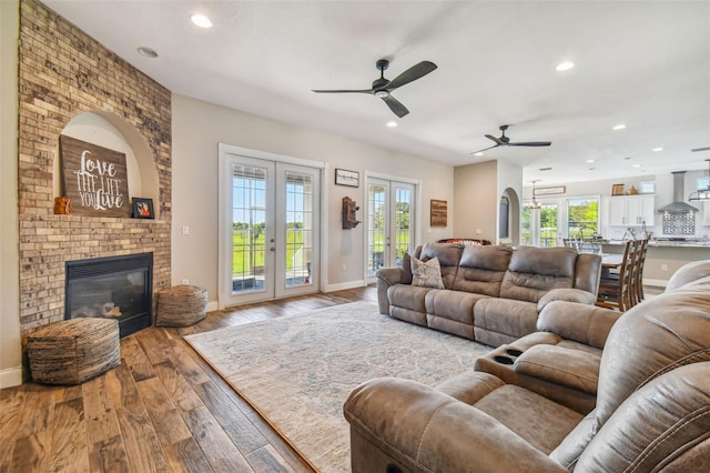 living room featuring light hardwood / wood-style floors, french doors, a fireplace, and ceiling fan