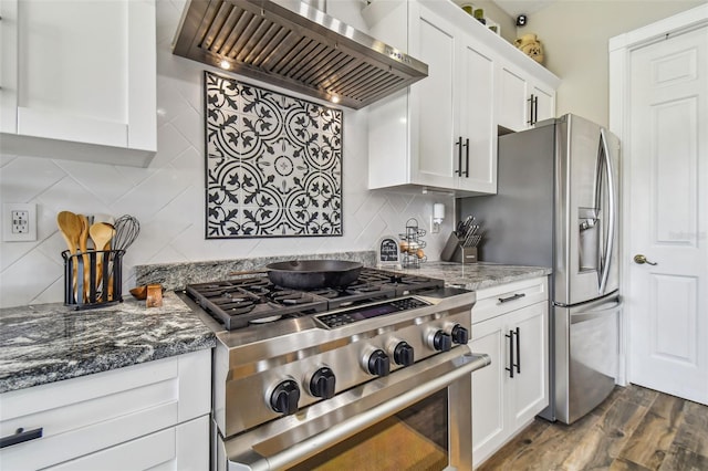 kitchen featuring stone counters, wall chimney range hood, stainless steel appliances, white cabinets, and dark hardwood / wood-style floors