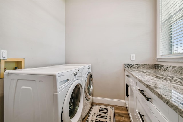 clothes washing area featuring cabinets, washing machine and clothes dryer, and dark hardwood / wood-style flooring