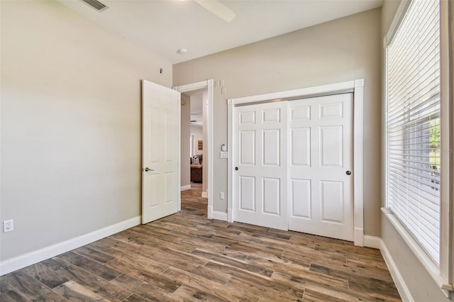 unfurnished bedroom with dark wood-type flooring, a closet, and ceiling fan