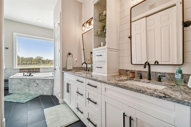 bathroom featuring vanity, a relaxing tiled tub, and tile patterned flooring