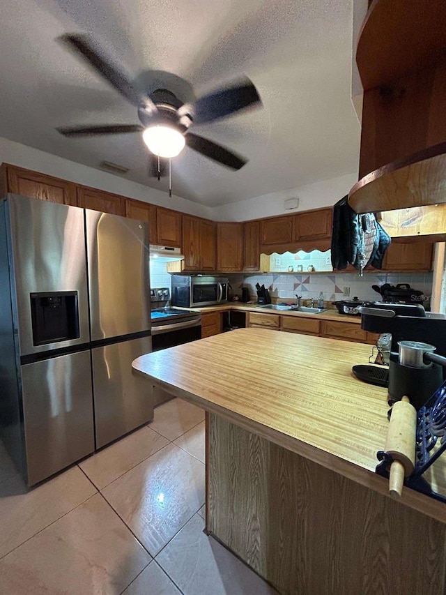 kitchen with a textured ceiling, sink, appliances with stainless steel finishes, light tile patterned floors, and ceiling fan