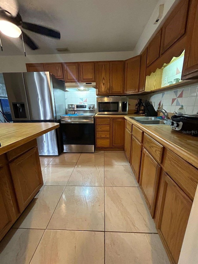 kitchen with light tile patterned floors, appliances with stainless steel finishes, backsplash, and sink