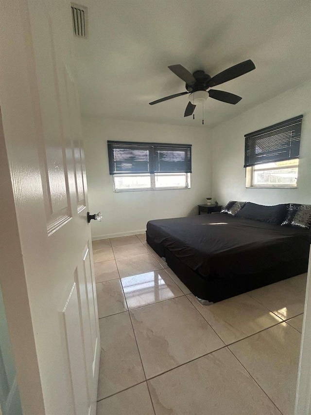 bedroom with ceiling fan, multiple windows, and light tile patterned flooring