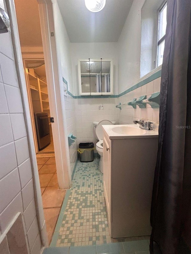 bathroom with vanity, tile walls, tile patterned flooring, and toilet