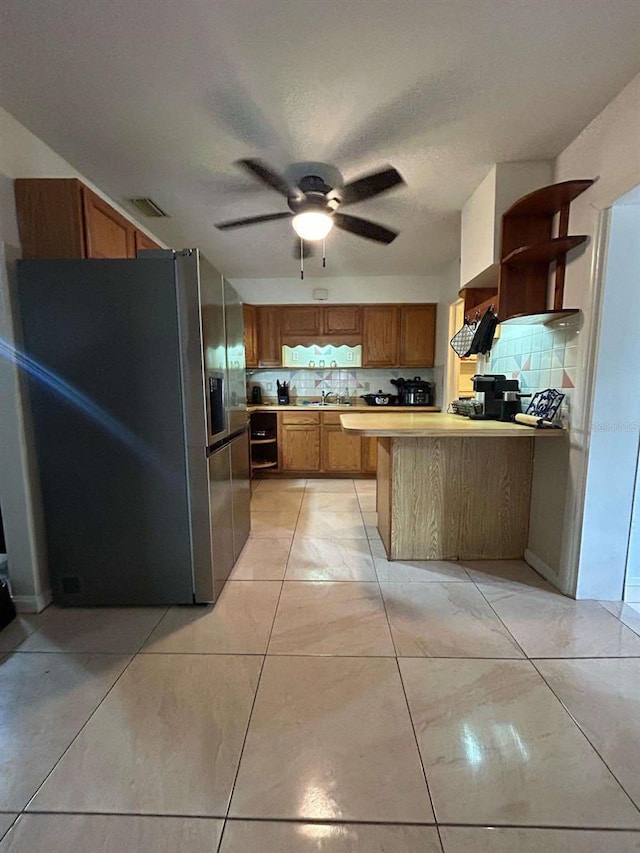 kitchen with decorative backsplash, kitchen peninsula, sink, and stainless steel fridge