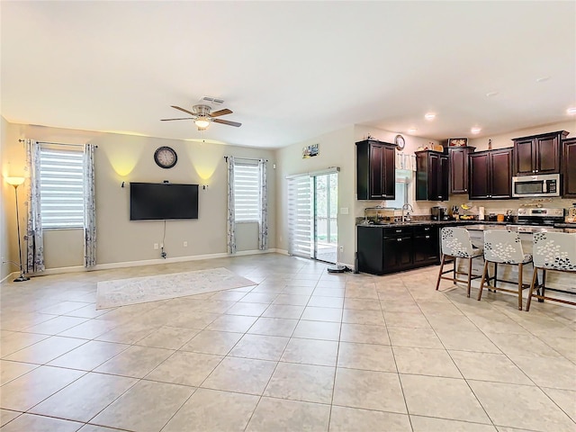 kitchen with open floor plan, stainless steel appliances, a kitchen breakfast bar, and light tile patterned flooring