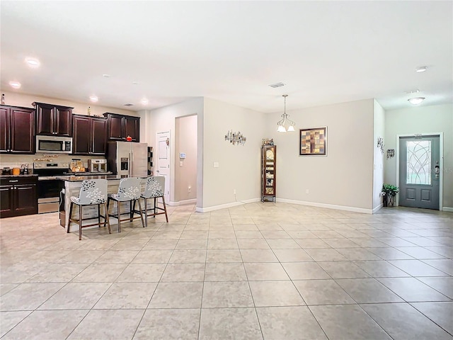 kitchen featuring light tile patterned floors, baseboards, a kitchen bar, and appliances with stainless steel finishes