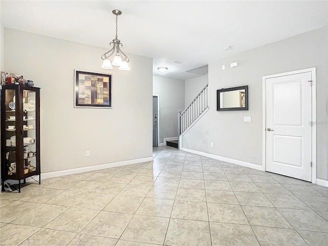 tiled empty room with an inviting chandelier