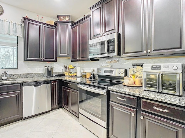 kitchen with tasteful backsplash, light stone counters, light tile patterned floors, and appliances with stainless steel finishes