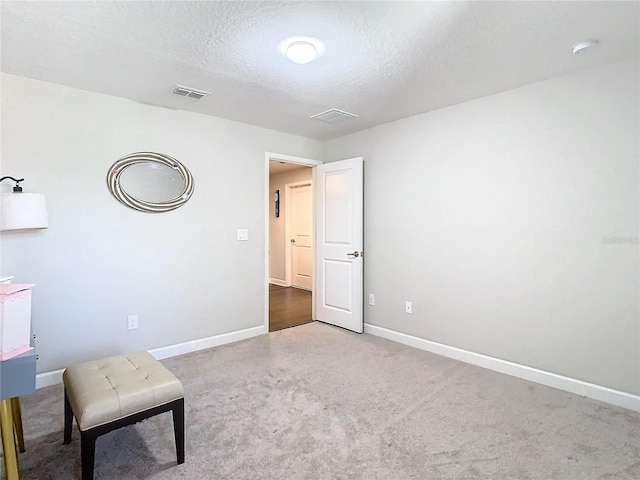 unfurnished room with carpet flooring, visible vents, a textured ceiling, and baseboards