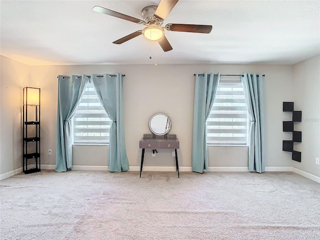 carpeted spare room featuring a healthy amount of sunlight, baseboards, and a ceiling fan